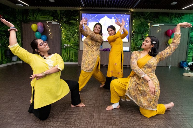 Students dressed in red traditional clothes dance in celebration of Diwali